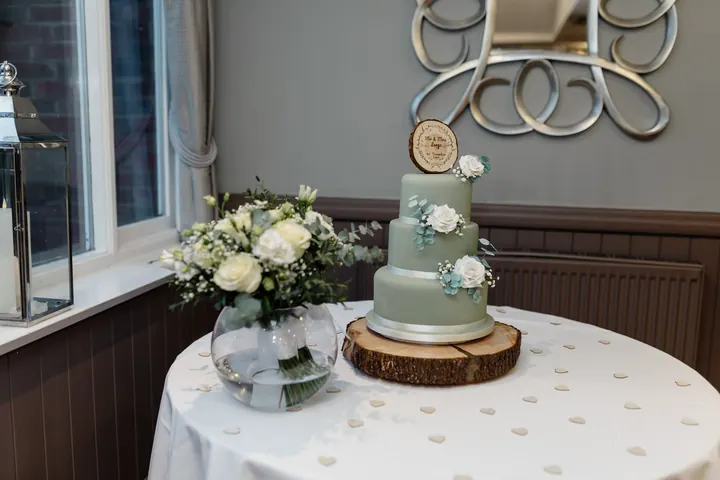 A three-tier sage green wedding cake with white roses