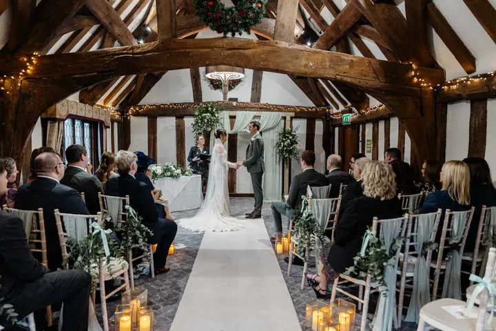 The ceremony beneath the oak beams, wreaths and fairy lights