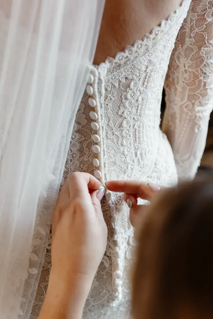 The buttons being fastened down the back of Sam&rsquo;s lace dress