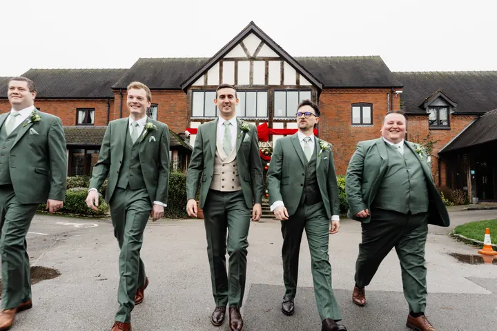 Andrew and the groomsmen walking up to the black and white front of The Moat House
