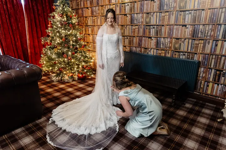A bridesmaid arranging Sam&rsquo;s train in the library, beside the Christmas tree