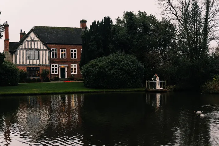 The Moat House across the water at dusk, with Sam and Andrew on the jetty