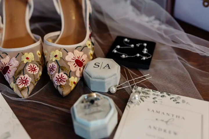 Embroidered floral bridal shoes beside a monogrammed ring box