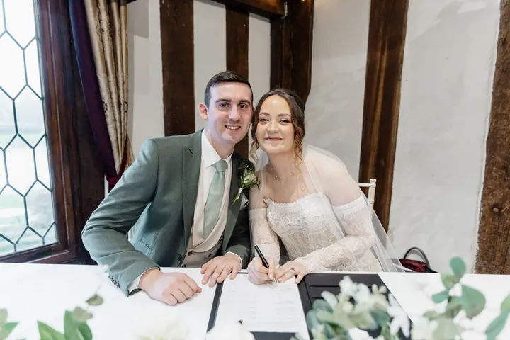 Sam and Andrew laughing as they sign the register