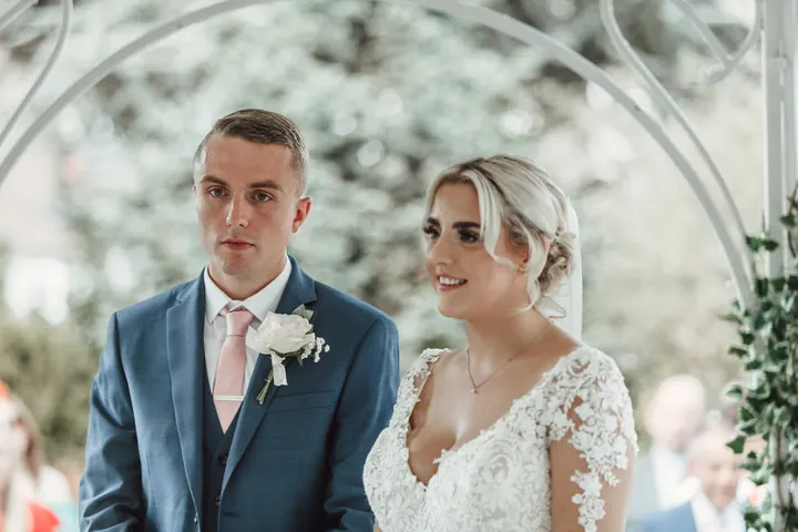 Sam and Sarah together under the floral arch