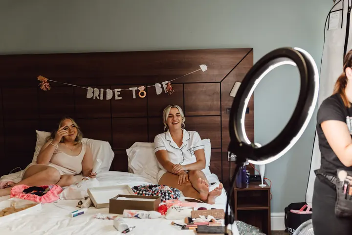 Sarah and a bridesmaid relaxing on the bed under a Bride To Be banner