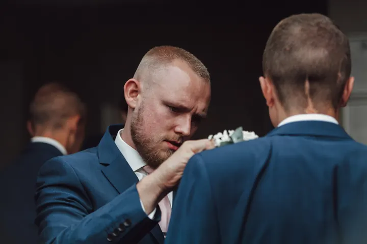 Pinning a white rose buttonhole onto a navy suit