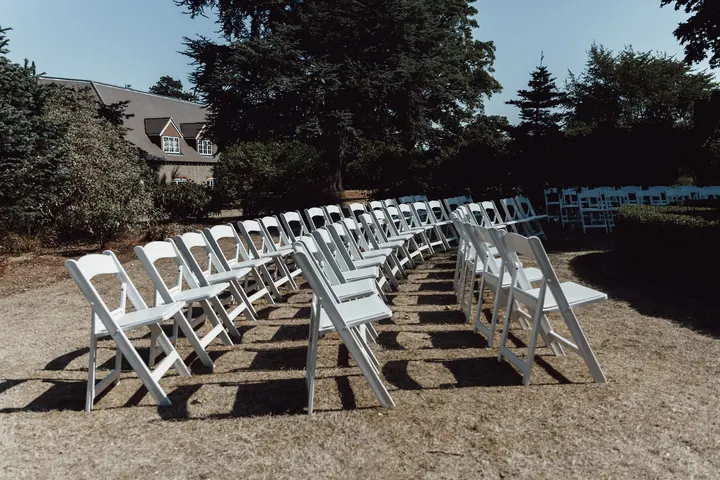 Rows of white chairs on the sun-scorched lawn