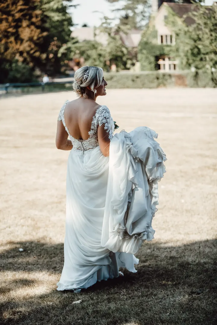Sarah holding up her dress on the sunlit lawn