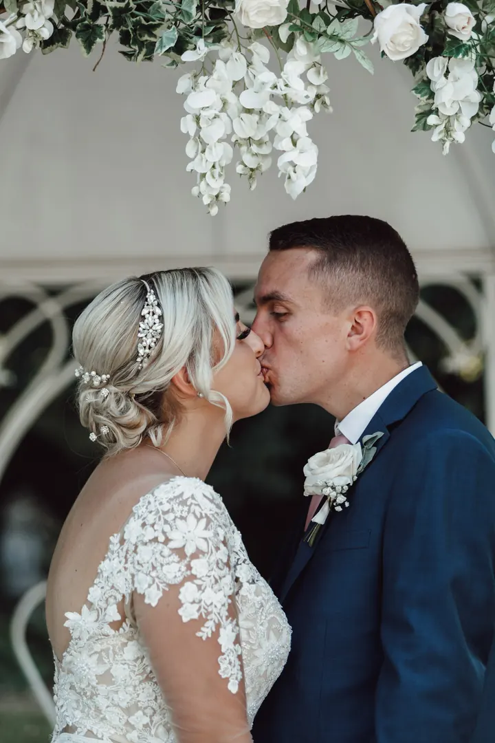A kiss beneath the white flowers of the gazebo