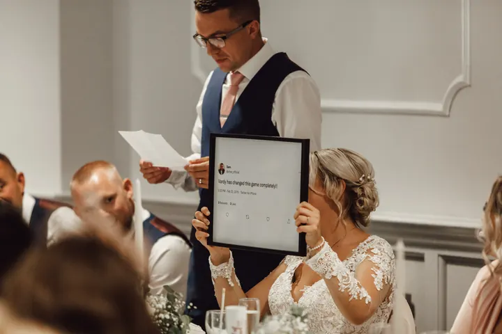 Sarah holding up a framed prop during the speeches