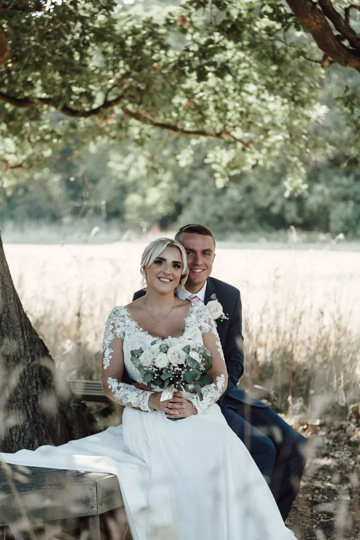 Sarah and Sam sitting beneath a tree beside a field of long golden grass
