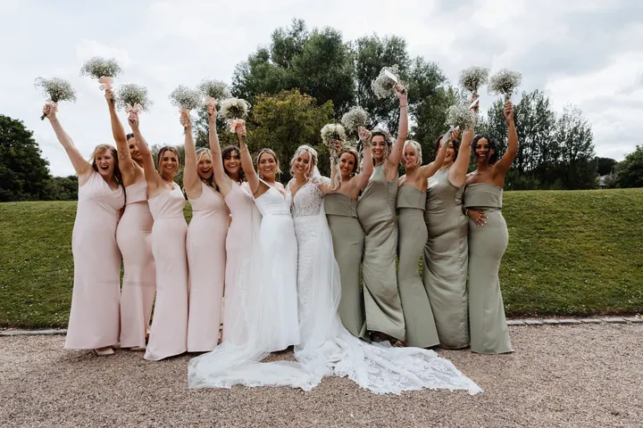 Both bridal parties cheering with gypsophila bouquets on the lawn