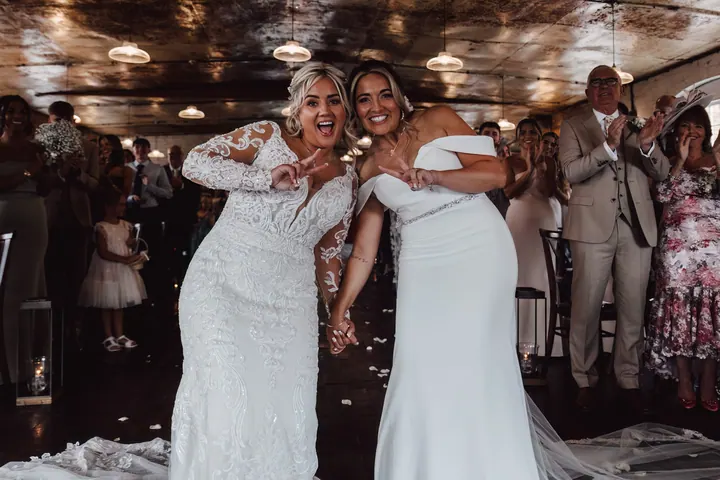 The brides celebrating, arms in the air, at the end of the ceremony
