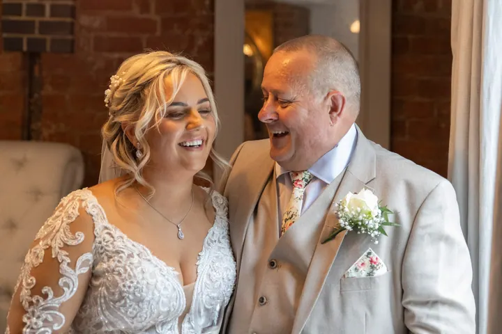 A bride laughing with her dad before the ceremony
