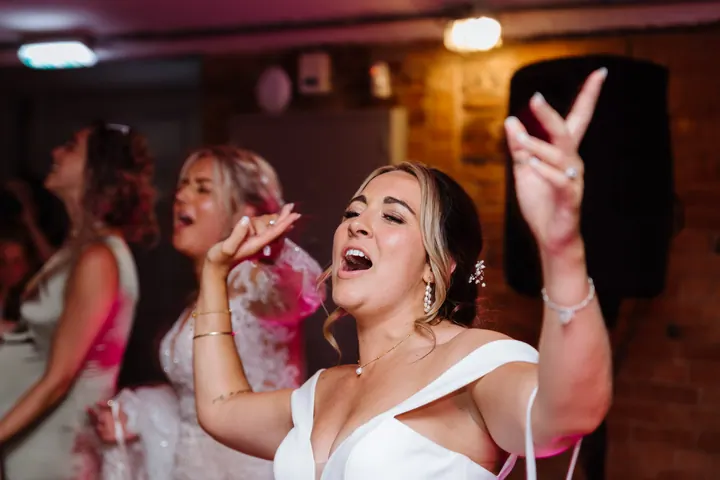 A bride singing on the dancefloor, arm in the air