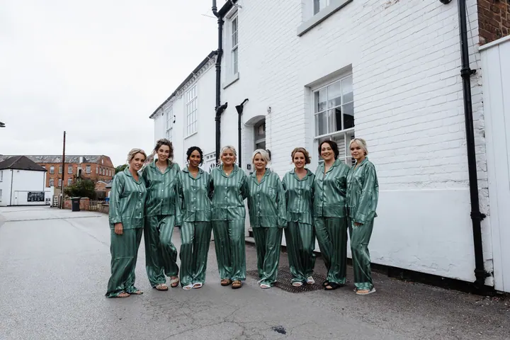 A bridal party in matching green pyjamas outside the mill cottages