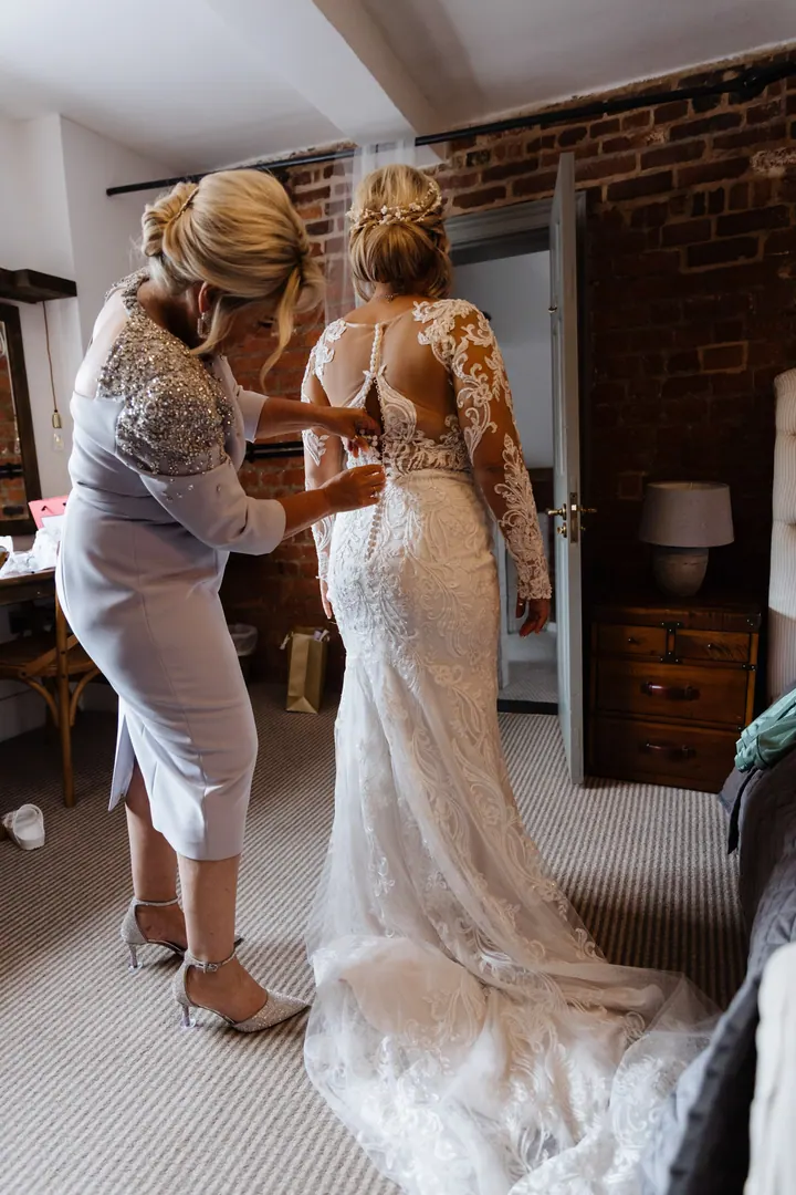 A bride being buttoned into her lace gown