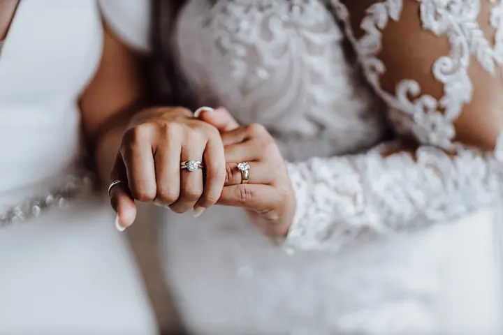 Two hands with wedding rings against lace