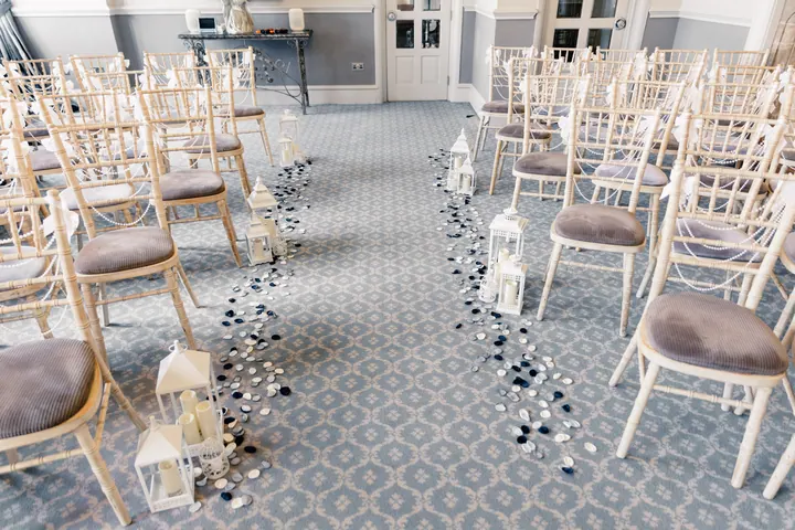 The ceremony room set with white chairs, petals and lanterns