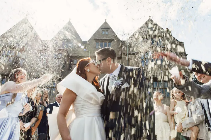 Guests throwing confetti in front of Weston Hall