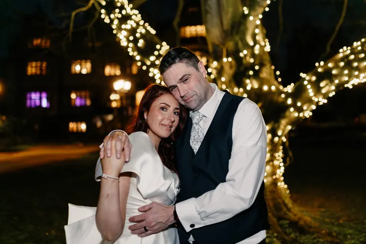 Laura and Darren beneath trees wrapped in fairy lights