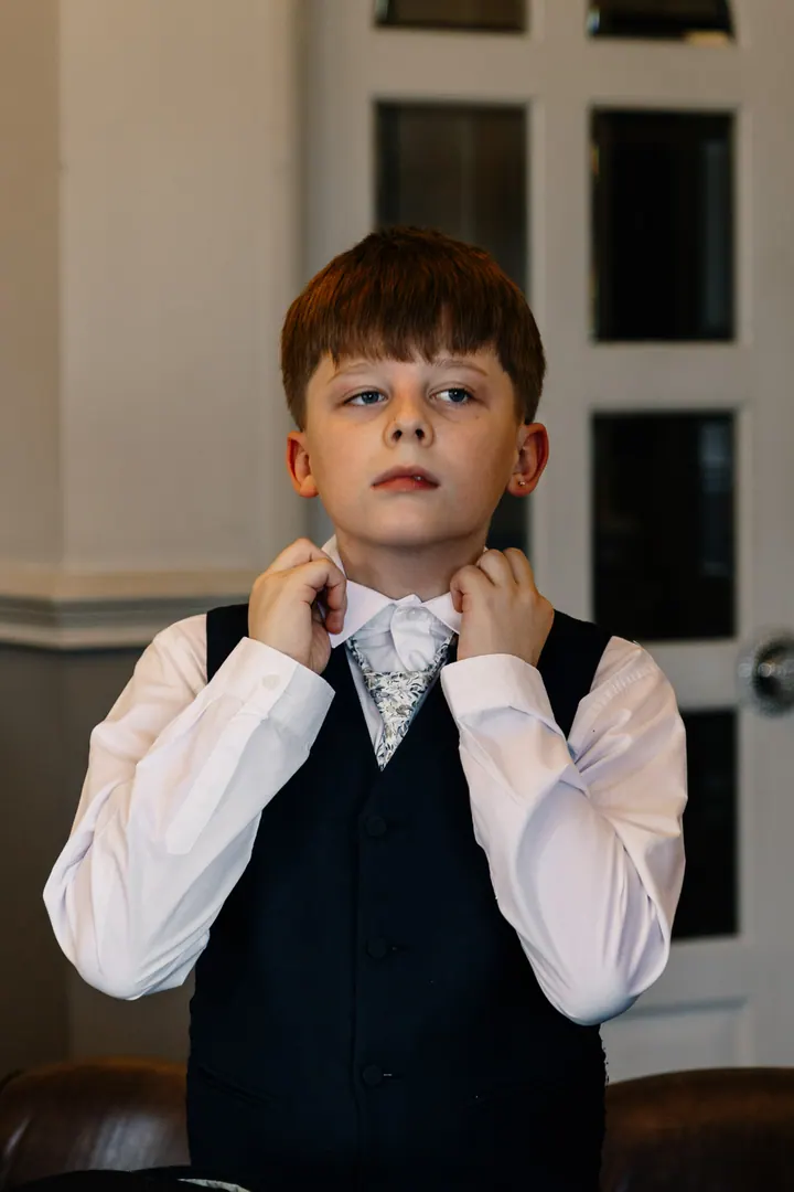 A page boy straightening his collar