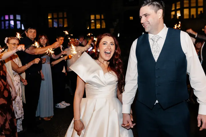 Laura laughing as she and Darren walk through a sparkler tunnel